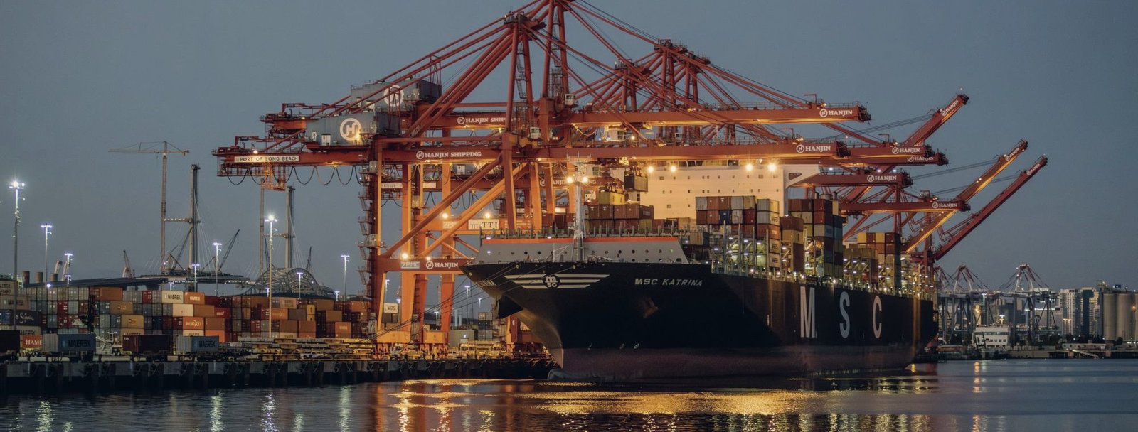 Gantry cranes at a container terminal, lit at dusk