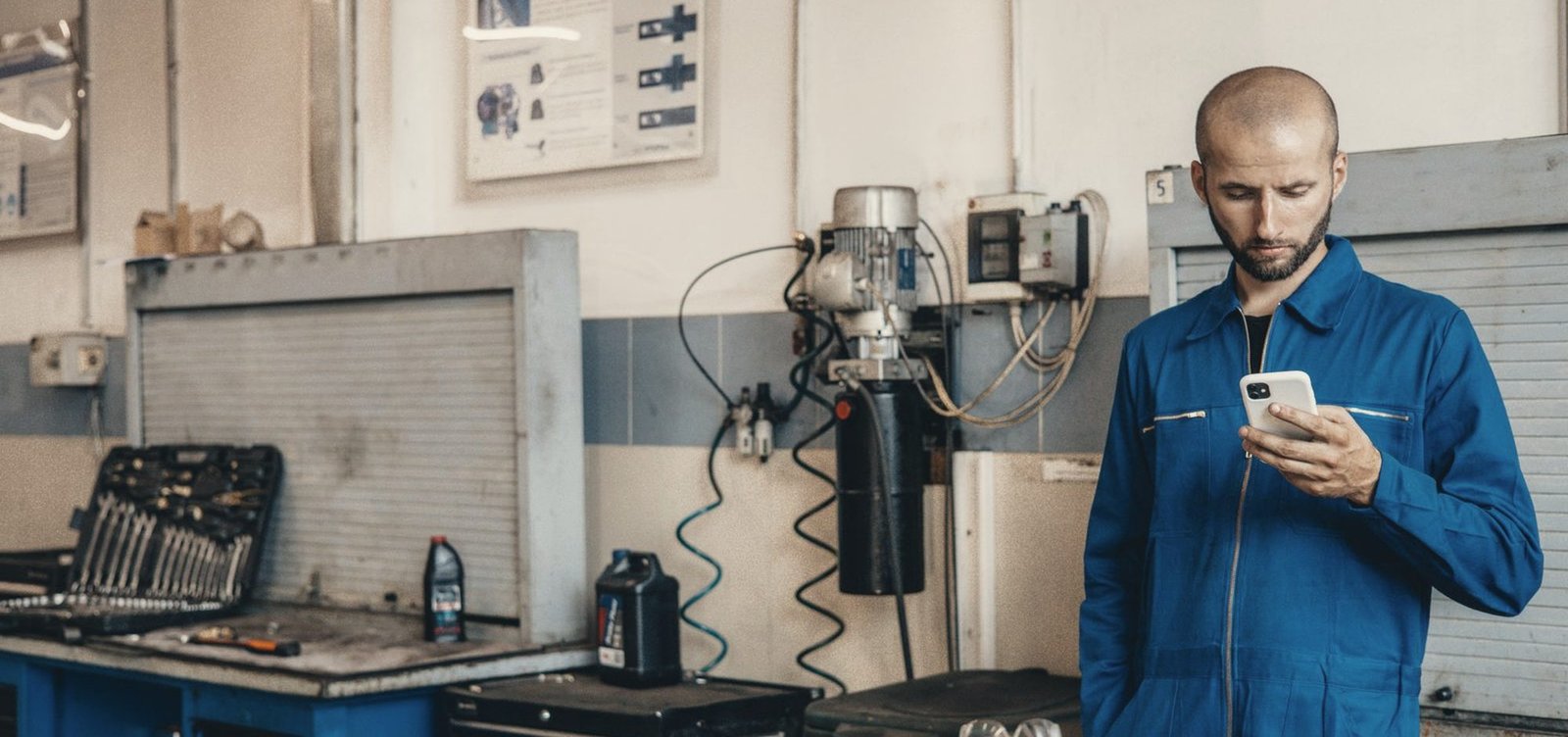 A mechanic checking his phone next to the workbench